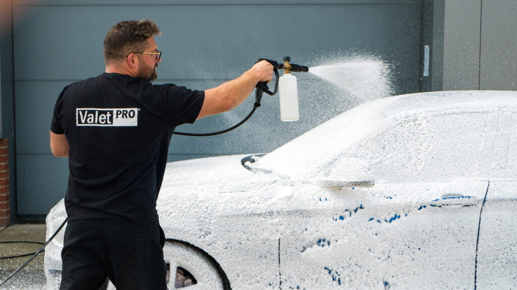 Detailer wearing a ValetPRO t-shirt applying pH Neutral Snow Foam to a car using a foam lance